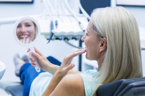 Older woman looking at her teeth in a mirror, nashville tn