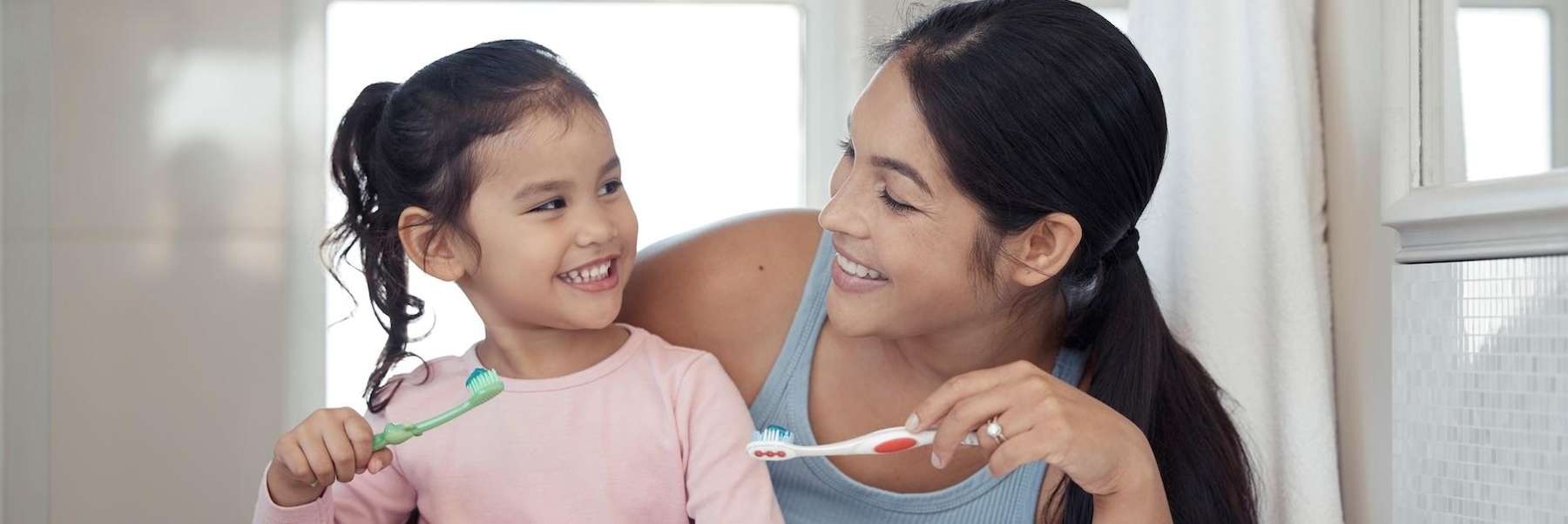 Young mom and girl smiling together brushing teeth, brentwood tn