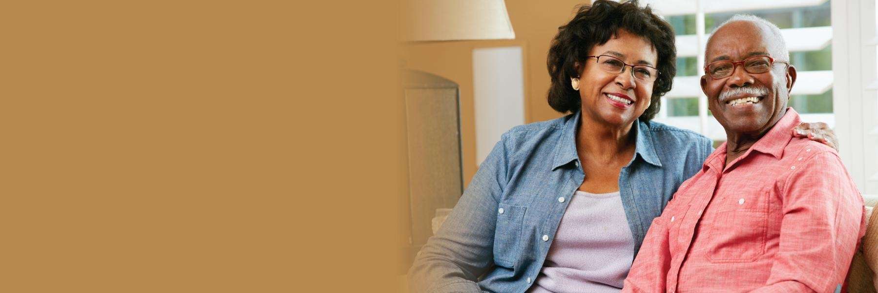 A couple smiling on the couch | implant dentures