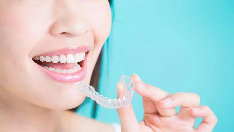 Woman holding an Invisalign tray | Invisalign Brentwood, TN