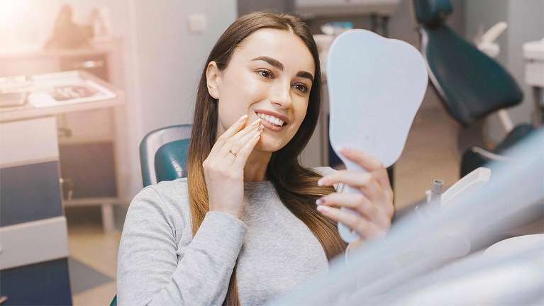 Woman looking at her completed dental work 