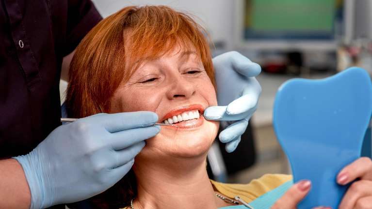 A woman examining her dentures | nashville dentist