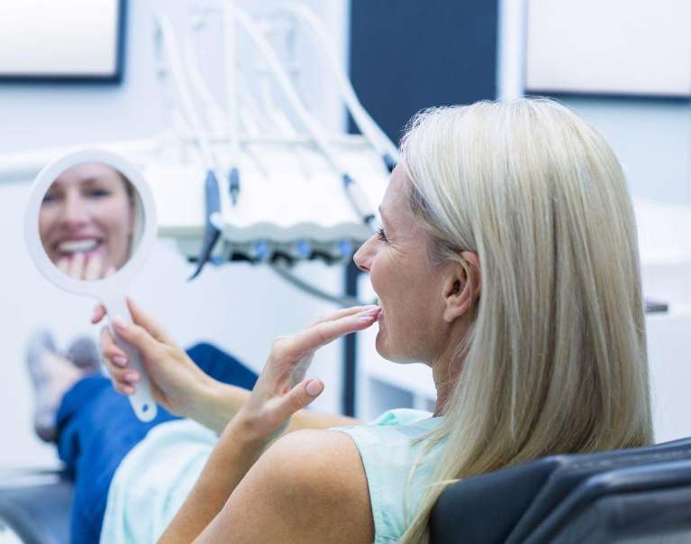 Woman looking at her teeth after cerec crowns, nashville tn
